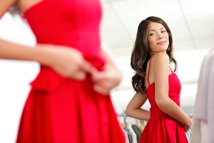 Girl trying dress in looking in mirror cheerful and happy. Cute beautiful mixed race Asian / Caucasian young woman oin red dress.